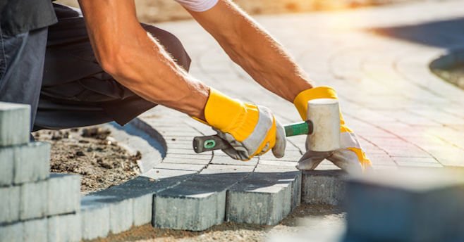 Construction worker laying paver blocks
